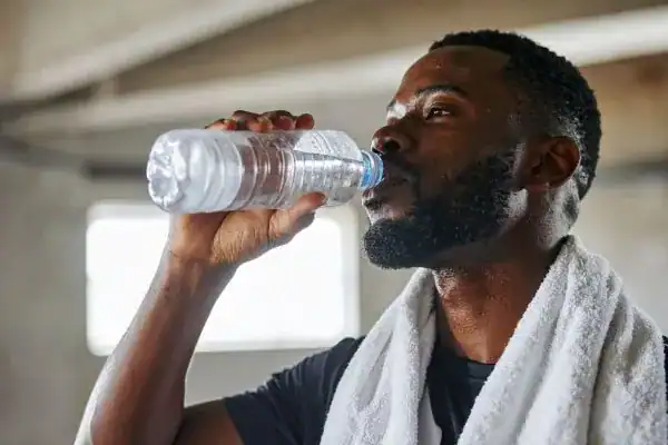 Image of man drinking water to improve hydration Royal Leamington Spa after work out.